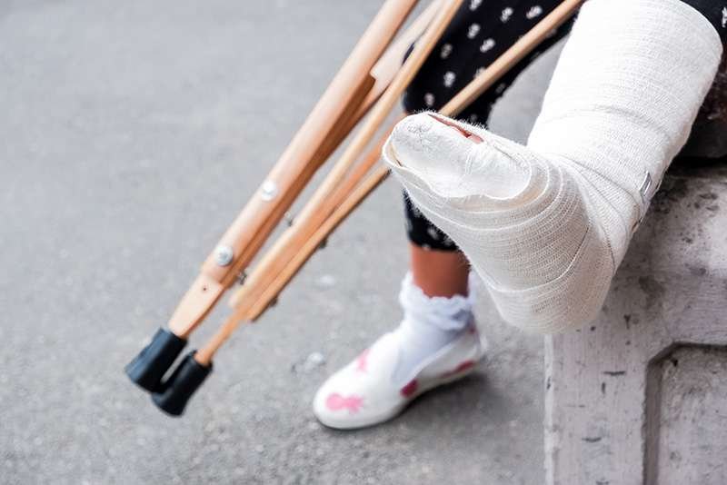 Person with bandaged leg using crutches.