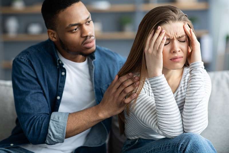 Man comforting distressed woman indoors.